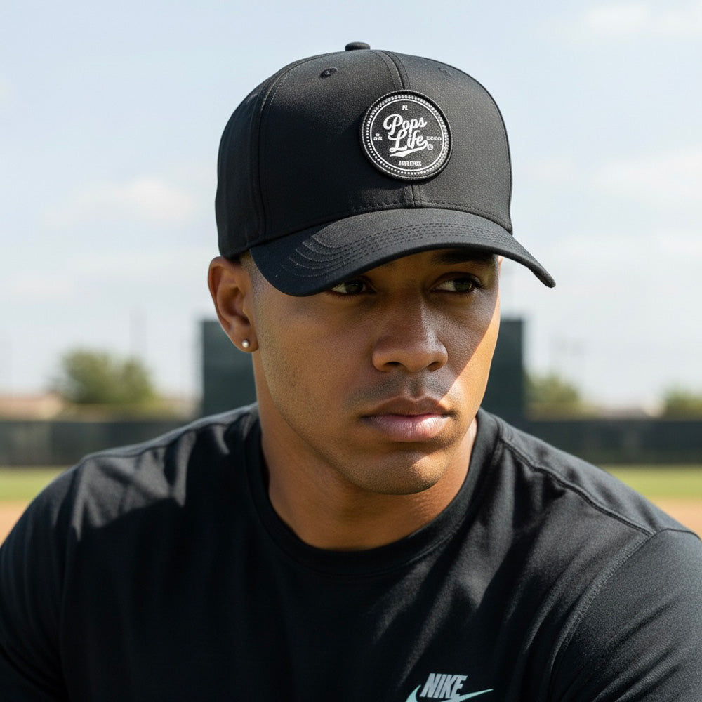 Man wearing a black cap with a logo and black Nike shirt on a blurred outdoor background