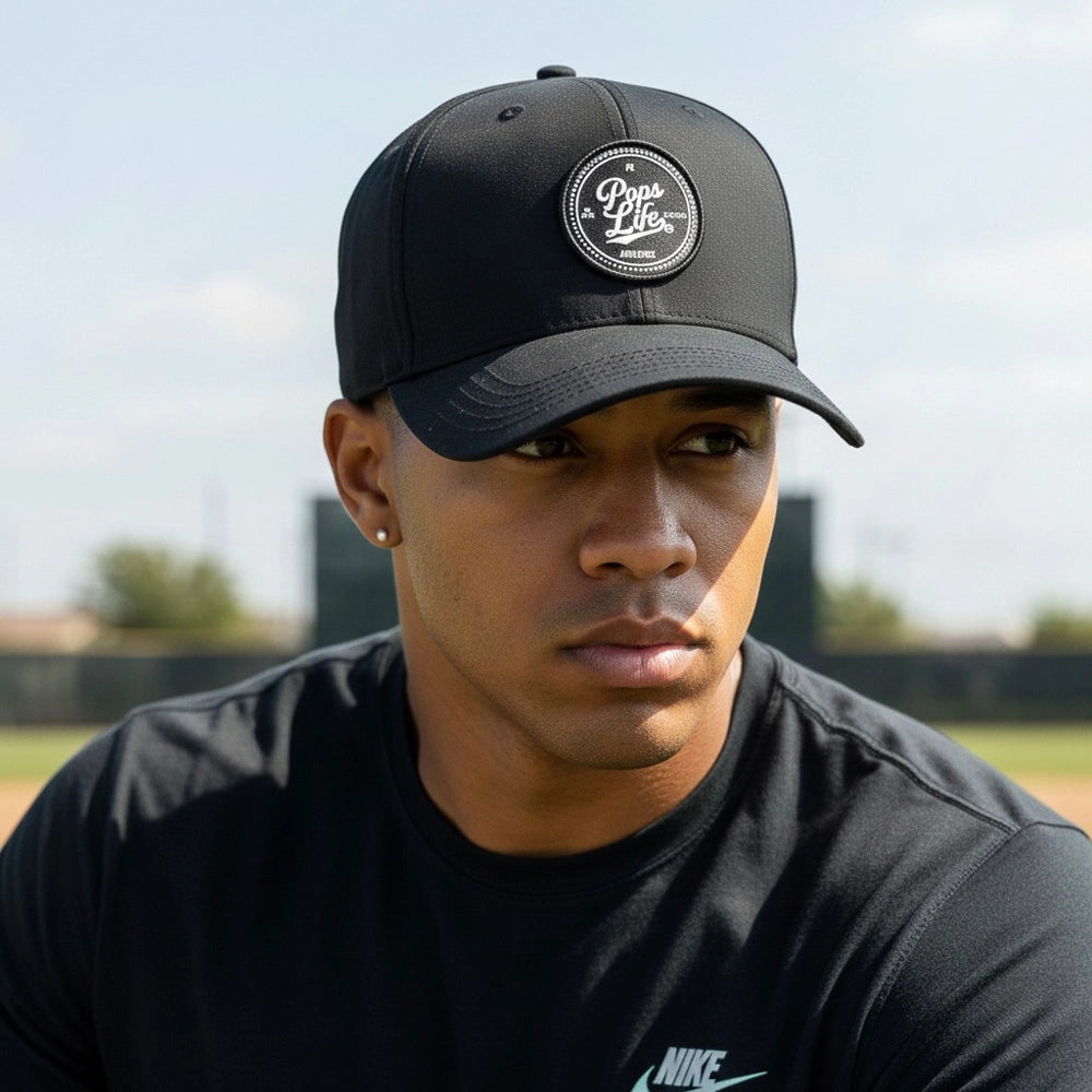 Man wearing a Pops Life Black Dad Hat with a logo and a black shirt on a blurred outdoor background