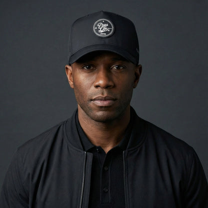 Man wearing a Pops Life Athletic Black Dad Hat and jacket against a dark background