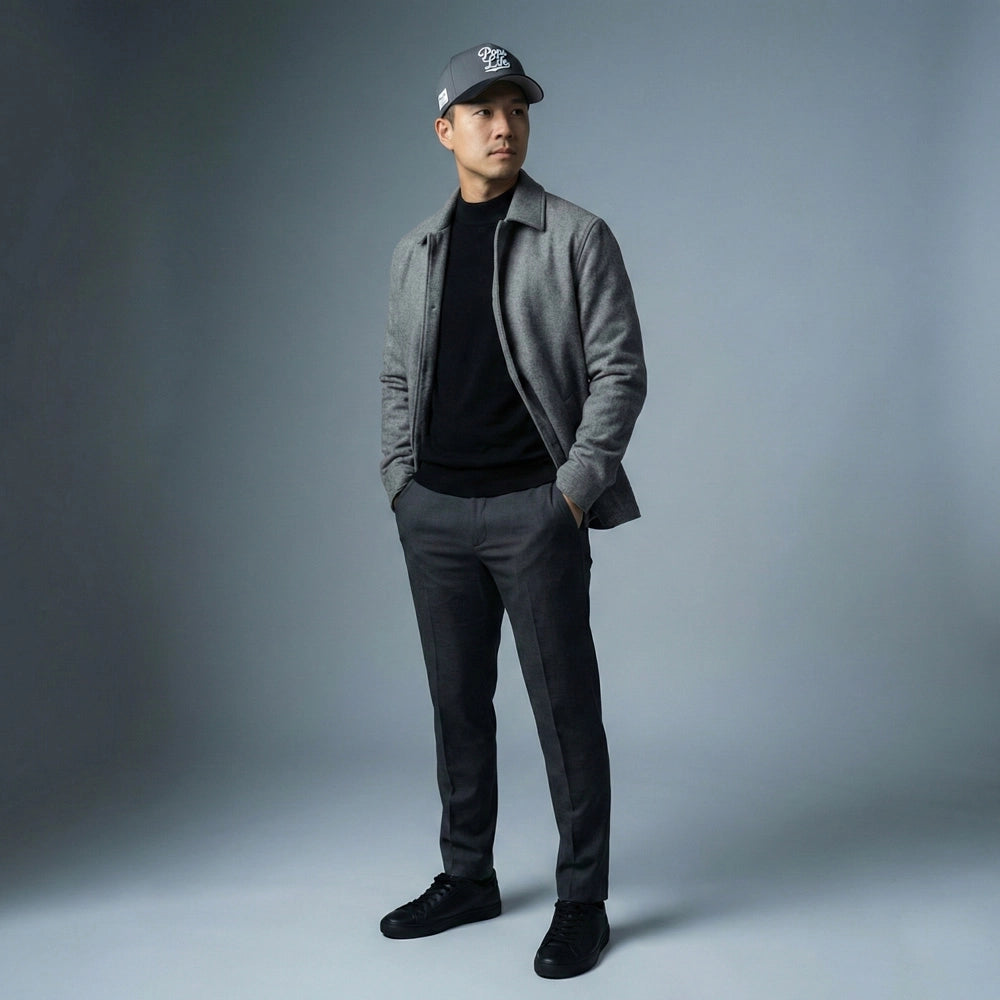 Man wearing a gray jacket, black shirt, gray pants, and black shoes with a Pops Life Gray and Black Dad Hat against a gray background