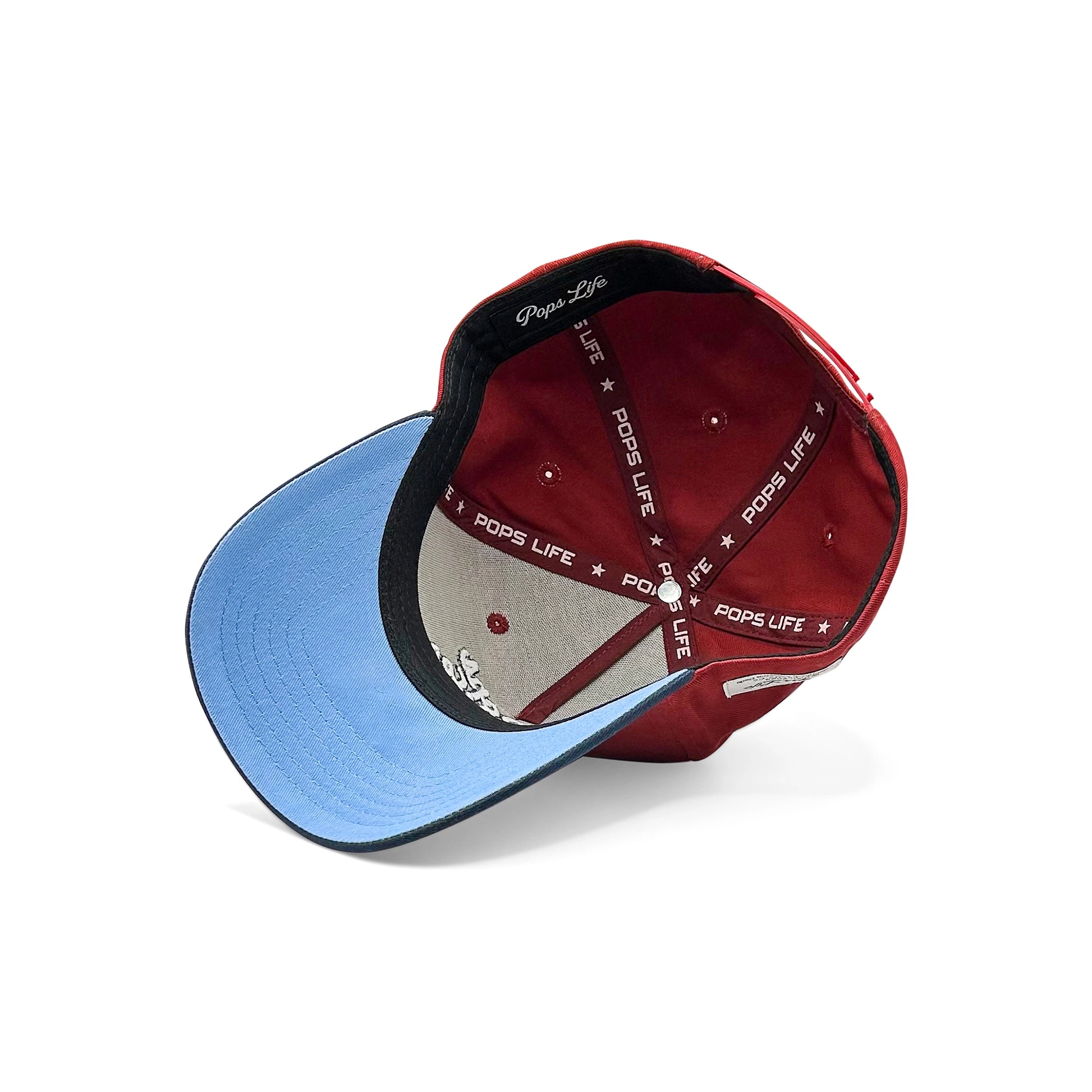 A view of the inside of the Pops Life Maroon Blue Dad Hat, showcasing the Pops Life branded taping and contrasting light blue underside of the brim.