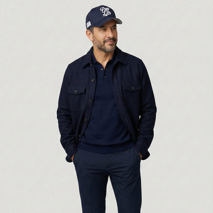 Man wearing a navy jacket, shirt, and Pops Life Navy blue Dad Hat on a light gray background