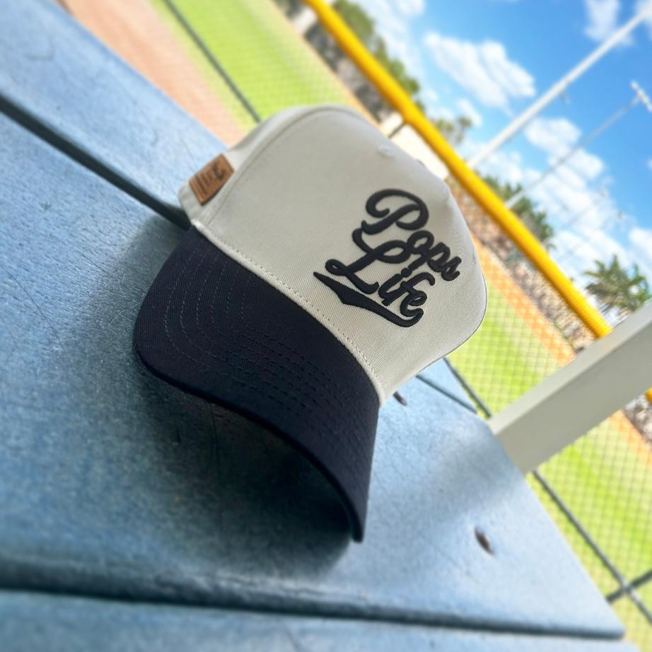 Quality dad hat on a baseball field bench, showcasing Pops Life brand design.